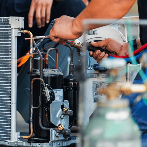 A technician brazing a copper line on an outdoor air conditioner