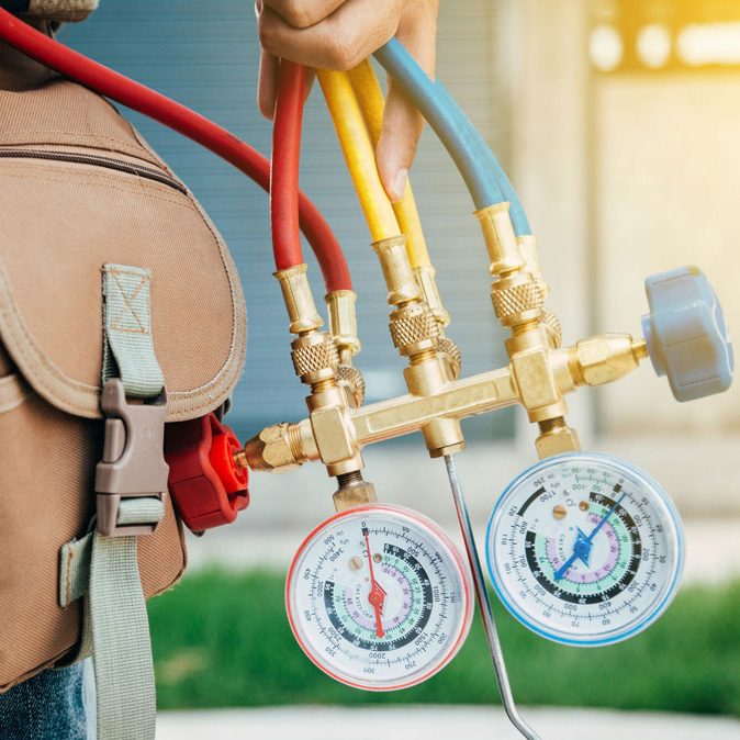 A technician holding a set of refrigerant gauges